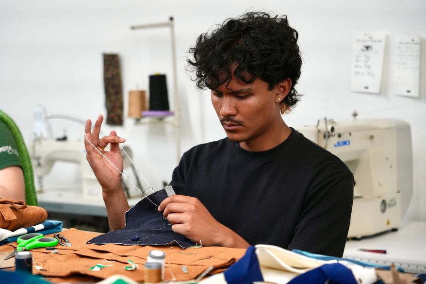 Jesse Sanchez practices sewing during a clothing repair workshop at a Levi's retail store in downtown San Francisco, Wednesday, July 22, 2026. (AP Photo/Terry Chea)