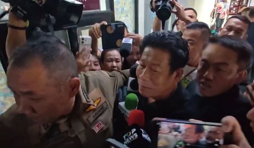 In this image made from video provided by the Thai Public Broadcasting Service, Chalong Riewraeng, center, former local Thai lawmaker, walks past media members in Nonthaburi, Thailand, Monday, Aug. 10, 2026. (TPBS via AP)