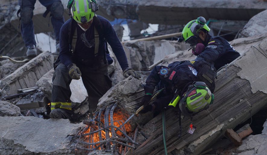 Rescue workers cut through debris as they search for survivors the day after an earthquake struck Cali, Colombia, Tuesday, Aug. 11, 2026. (AP Photo/Ivan Valencia)