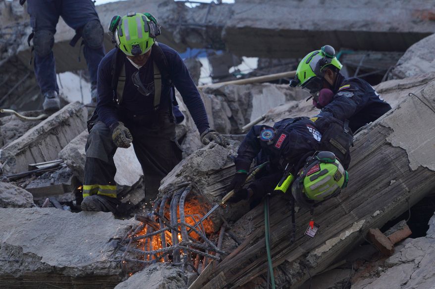 Rescue workers cut through debris as they search for survivors the day after an earthquake struck Cali, Colombia, Tuesday, Aug. 11, 2026. (AP Photo/Ivan Valencia)
