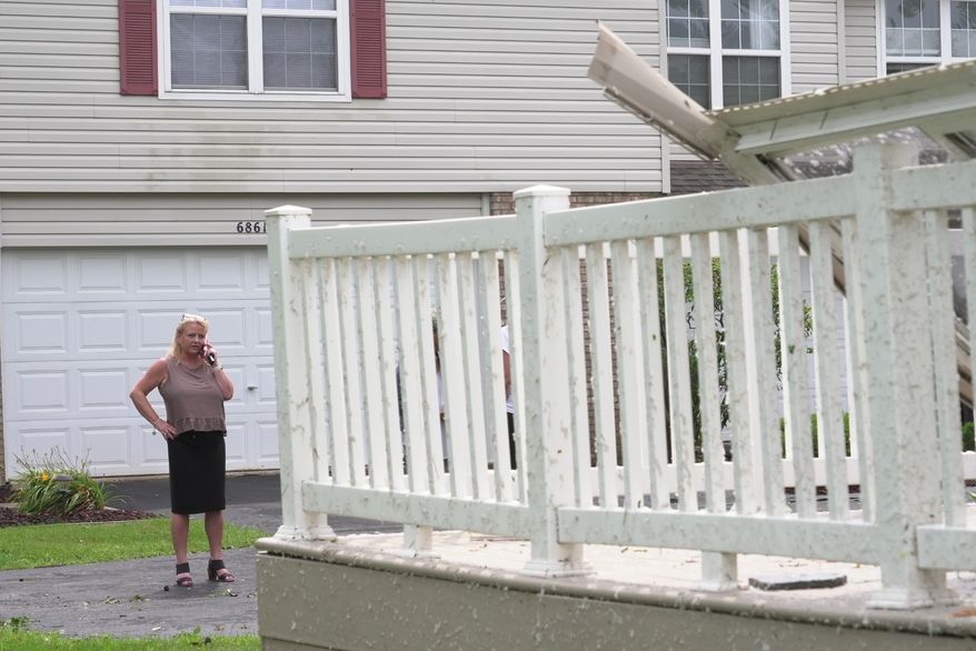 Kerry Hourigan speaks on the phone after reviewing damage a storm caused to her home in Tinley Park, Ill., Tuesday, Aug. 11, 2026. (AP Photo/Laura Bargfeld)