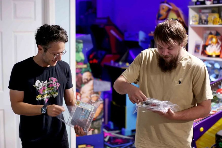 In this photo provided by Nintendo Wire, publisher Jason Ganos, left, and OneStopWonders store owner Kevin Braun hold PSA graded copies of Super Mario Bros. and Duck Hunt video games on Wednesday, June 17, 2026, which they rediscovered in a warehouse in Waukesha, Wis. (Lauren Ganos/Nintendo Wire via AP)