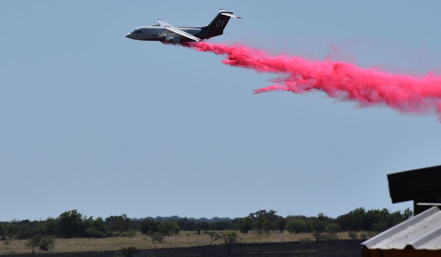 A tanker aircraft dumps fire retardant on a field southwest of Salado, Texas, Wednesday, Aug. 12, 2026, after a military helicopter crashed and sparked a grass fire. (Brent Johnson/The Killeen Daily Herald via AP)