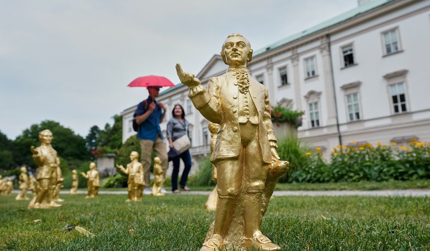 FILE - People walk by some of the 400 gold colored plastic Mozart sculptures by German artist Ottmar Hoerl from Nuremberg for the 270th birthday of composer Wolfgang Amadeus Mozart in Salzburg, Austria, Wednesday, July 15, 2026. (AP Photo/Matthias Schrader, File)