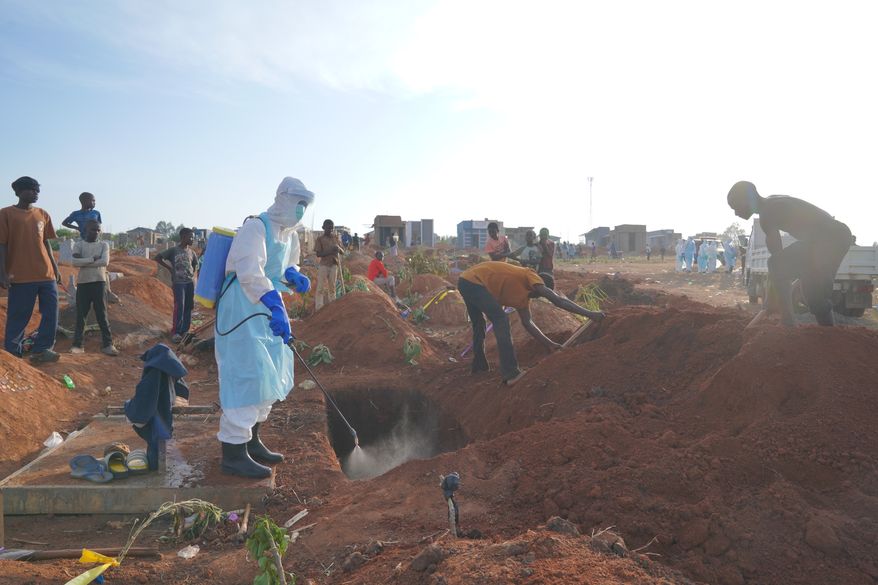 A health worker sprays disinfectant in a freshly dug grave for the body of Jacques Lobo Dhena, who died of Ebola, in Bunia, Ituri province, eastern Congo, Wednesday, Aug. 12, 2026. (AP Photo/Dieudonne Dirole)