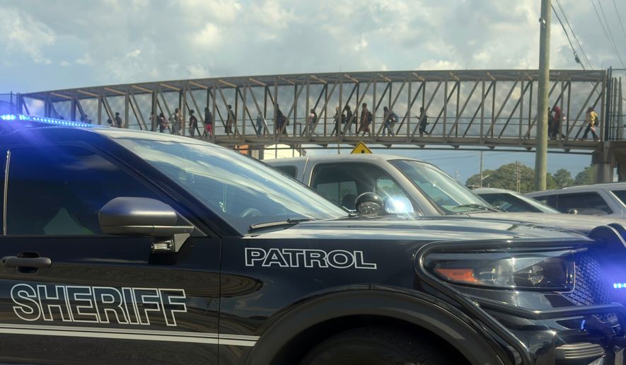 Students leave Warner Robins High School as Houston County Sheriff vehicles remain on the scene after a shooting at the school Wednesday, Aug. 12, 2026, in Warner Robins, Ga. (Joe Kovac/Atlanta Journal-Constitution via AP)