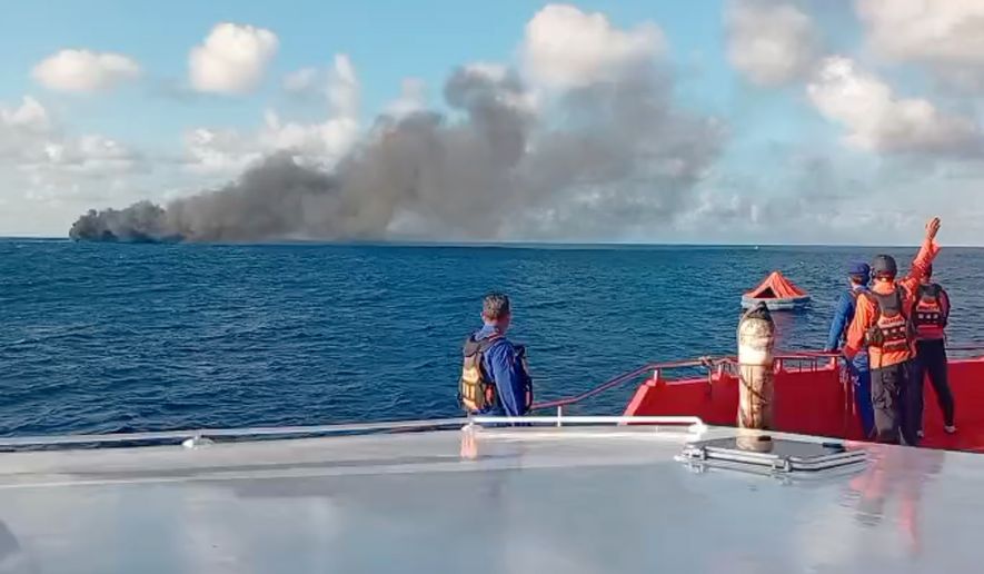 In this image made from video released by the Indonesian National Search and Rescue Agency (BASARNAS), the crew of a rescue ship look on as smoke billows from a passenger ferry that caught fire while traveling from the tourist island of Bali to neighboring island of Lombok, in the waters of Lombok Strait, Indonesia, Wednesday, Aug. 12, 2026. (BASARNAS via AP)