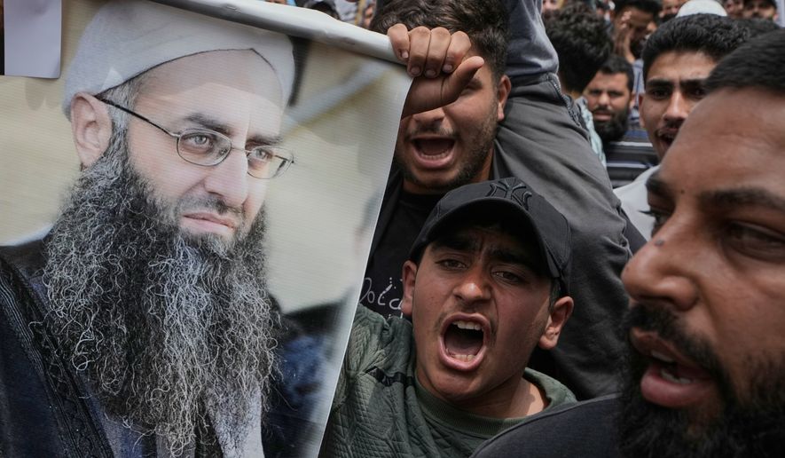 FILE - Sunni Muslims hold a portrait of imprisoned Sunni cleric Ahmad al-Assir during a protest against a clause in a proposed amnesty law that would exclude some prisoners, including the cleric, from being eligible for amnesty, after Friday prayers in Beirut, Lebanon, Friday, May 22, 2026. (AP Photo/Bilal Hussein, File)