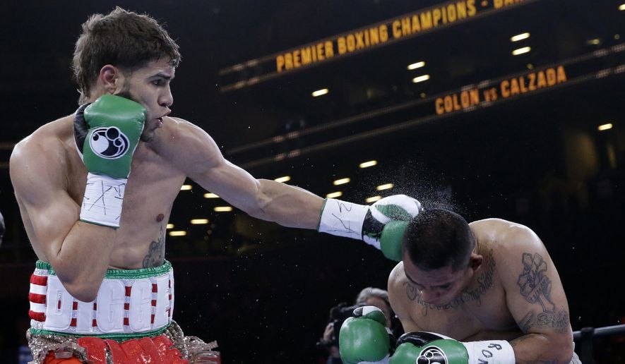 Prichard Colon, left, punches Daniel Calzada during a junior middleweight title boxing match, Saturday, April 11, 2015, at New York. Colon won by TKO. (AP Photo/Mary Altaffer)