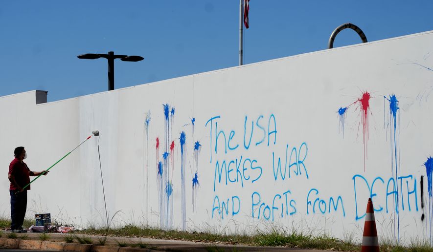 A worker paints to remove protest graffiti on a wall of the U.S. Embassy in Brasília, Brazil, Thursday, Aug. 13, 2026. (AP Photo/Eraldo Peres)