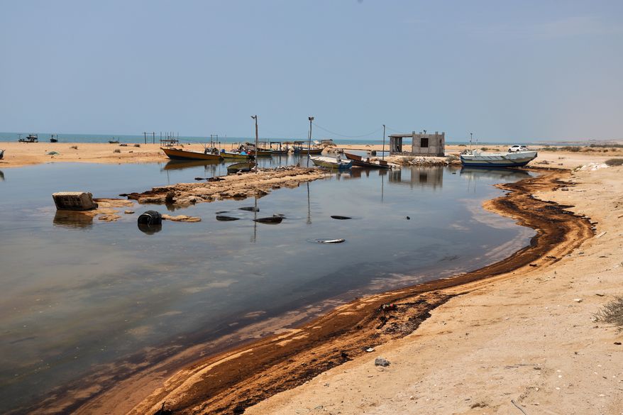 Oil residue lines the shore near fishing boats on Qeshm Island, Iran, Thursday, Aug. 13, 2026, amid ongoing wartime attacks on vessels and infrastructure in and around the Strait of Hormuz, though the spill's source has not been independently determined. (Amirhosein Khorgooi/ISNA via AP)