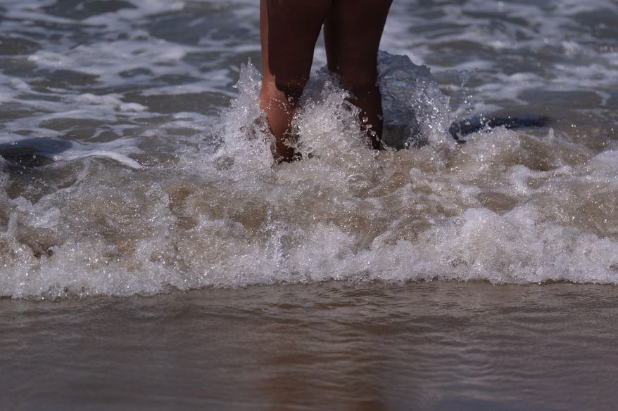 A beachgoer stands in shallow water at Bolsa Chica State Beach in Huntington Beach, Calif., Friday, July 24, 2026. (AP Photo/Jae C. Hong)
