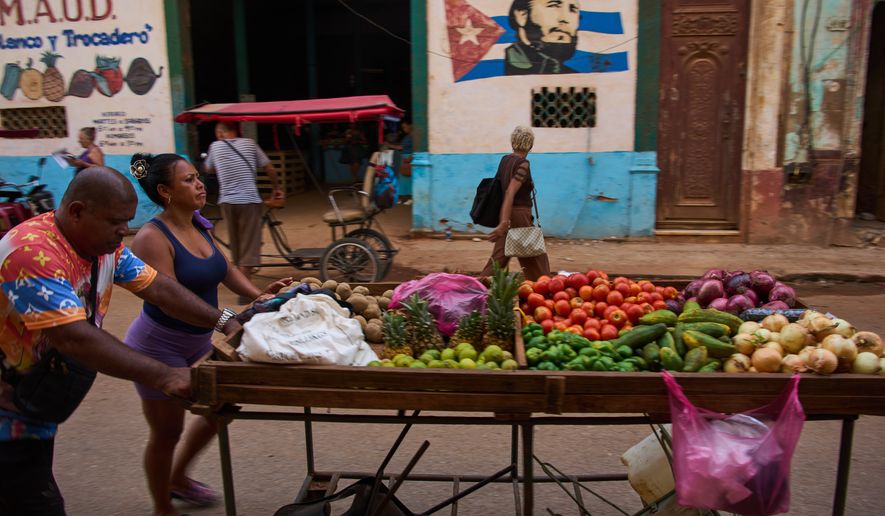 Street vendors push their cart of vegetables past a mural of Fidel Castro in Havana, Cuba, Wednesday, Aug. 12, 2026. (AP Photo/Ramon Espinosa)