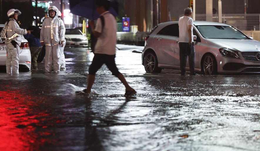 Record-breaking torrential rain floods a road, causing a car to stall, in Ichikawa, Chiba prefecture, Japan, on Thursday, Aug. 13, 2026. (Kyodo News via AP)