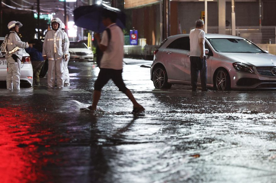 Record-breaking torrential rain floods a road, causing a car to stall, in Ichikawa, Chiba prefecture, Japan, on Thursday, Aug. 13, 2026. (Kyodo News via AP)