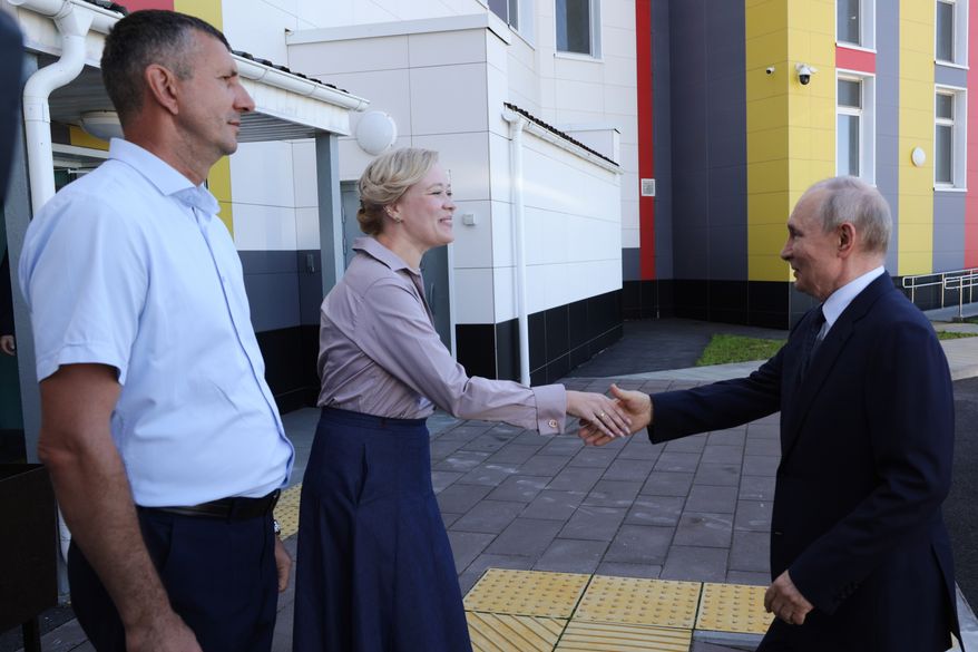 Russian President Vladimir Putin, right, visits the Secondary School named after the Hero of Russia Eduard Norpolov in Kurilsk on the Iturup Island, the largest of the Kuril Islands of Russia's fareast, on Thursday, Aug. 13, 2026. (Gavriil Grigorov, Sputnik, Kremlin Pool Photo via AP)