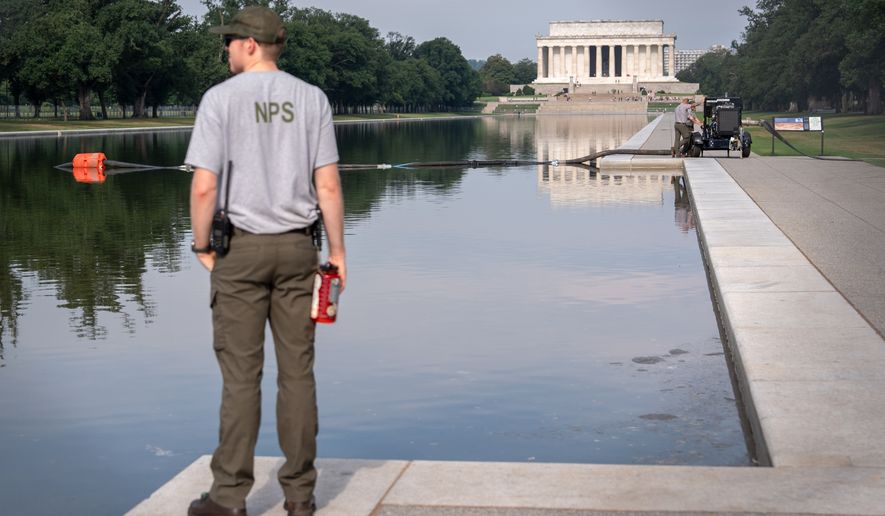 FILE - A National Park Service worker stands near a pump placed next to the Lincoln Memorial Reflecting Pool in Washington, July 10, 2026. (AP Photo/Mark Schiefelbein, File)