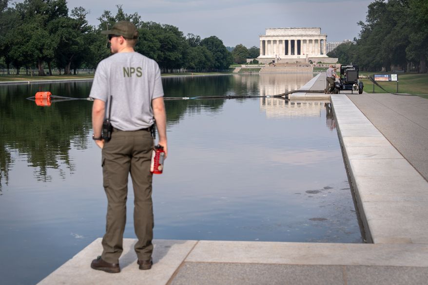 FILE - A National Park Service worker stands near a pump placed next to the Lincoln Memorial Reflecting Pool in Washington, July 10, 2026. (AP Photo/Mark Schiefelbein, File)