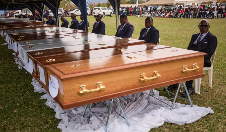 Funeral pallbearers sit behind caskets during a memorial service for the victims of a ferry capsized on lake Kariba in Kariba, Zimbabwe, Thursday, Aug. 13, 2026. (AP Photo/Mkhululi Thobela)