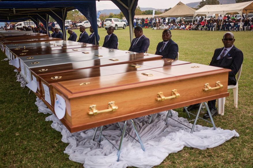 Funeral pallbearers sit behind caskets during a memorial service for the victims of a ferry capsized on lake Kariba in Kariba, Zimbabwe, Thursday, Aug. 13, 2026. (AP Photo/Mkhululi Thobela)