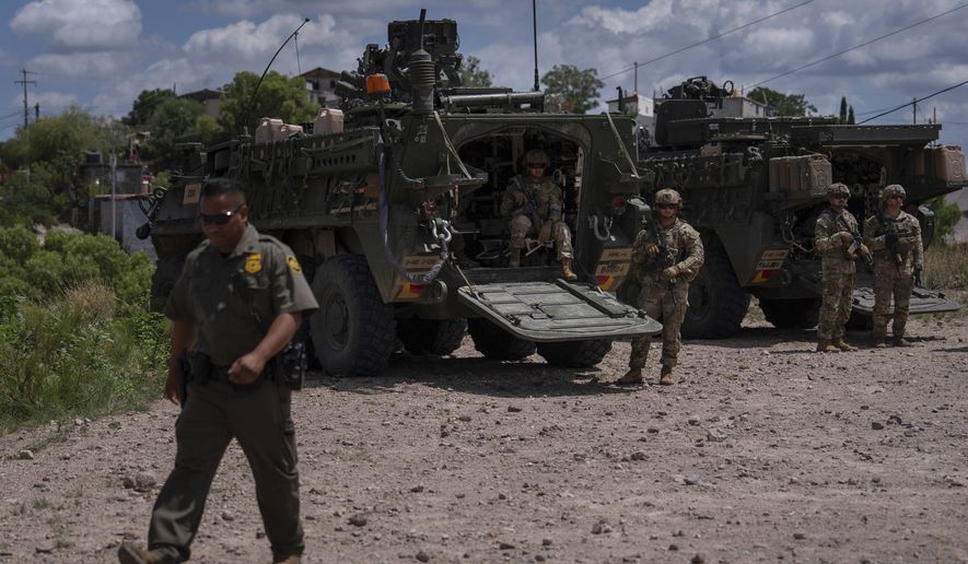 U.S. Army soldiers stand next to Stryker combat vehicles on a hilltop overlooking the U.S.-Mexico border fence in Nogales, Ariz., Tuesday, July 22, 2025. (AP Photo/Jae C. Hong)
