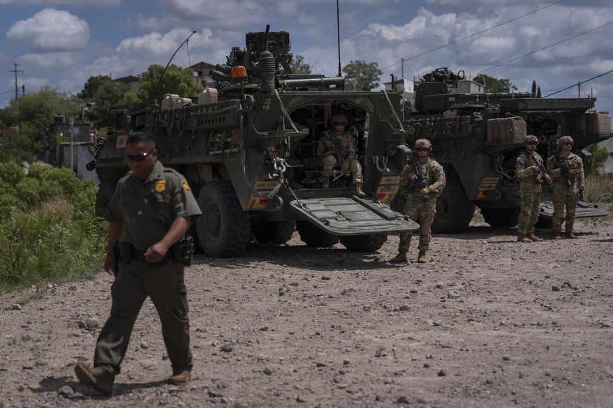 U.S. Army soldiers stand next to Stryker combat vehicles on a hilltop overlooking the U.S.-Mexico border fence in Nogales, Ariz., Tuesday, July 22, 2025. (AP Photo/Jae C. Hong)