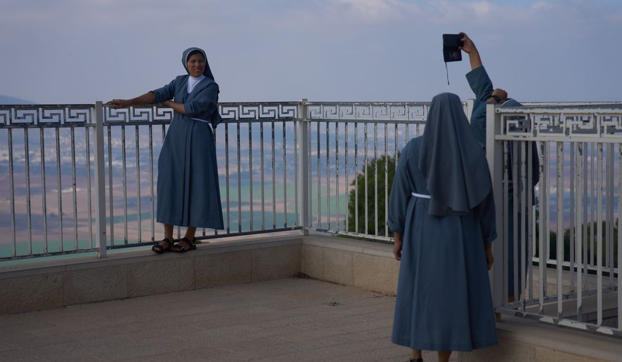 Nuns pose for photograph with the view from the Basilica of the Transfiguration on Mount Tabor, northern Israel, Aug. 6, 2026. (AP Photo/Ariel Schalit)