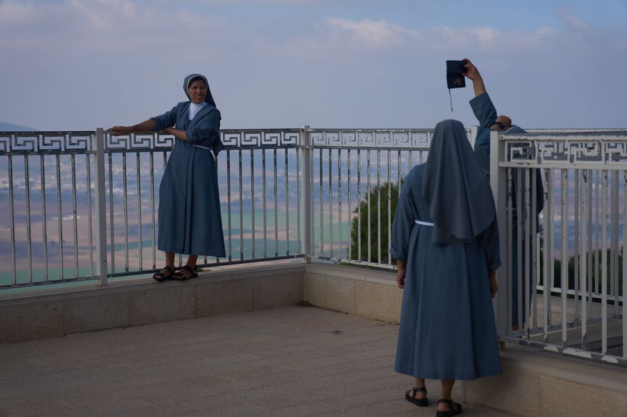 Nuns pose for photograph with the view from the Basilica of the Transfiguration on Mount Tabor, northern Israel, Aug. 6, 2026. (AP Photo/Ariel Schalit)