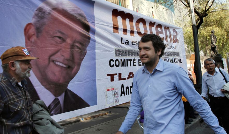 FILE - Andres Lopez Beltran, center, walks past a banner featuring an image of his father, Andres Manuel Lopez Obrador, in Mexico City, Dec. 6, 2013. (AP Photo/Marco Ugarte, File)