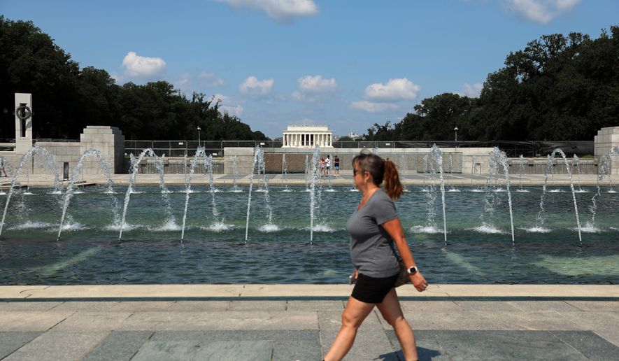 A woman walks near the fountain at the WWII Memorial, in Washington, Wednesday, July 29, 2026. (AP Photo/Rahmat Gul)