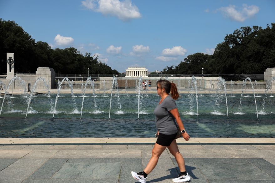 A woman walks near the fountain at the WWII Memorial, in Washington, Wednesday, July 29, 2026. (AP Photo/Rahmat Gul)