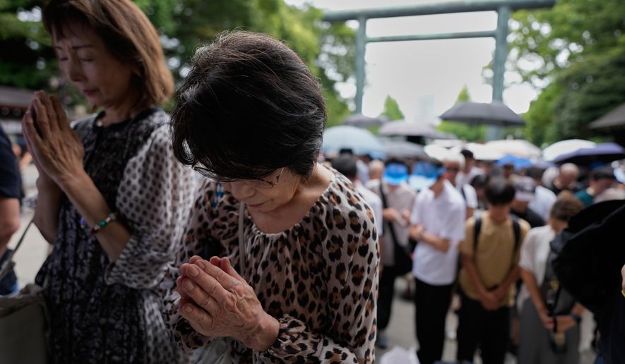 Visitors observe a moment of silence at Yasukuni Shrine, which honors Japan's war dead, including convicted war criminals, as the country marks the 81st anniversary of the end of World War II Saturday, Aug. 15, 2026, in Tokyo. (AP Photo/Eugene Hoshiko)