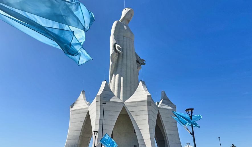 Flags wave in the wind in front of an enormous statue of the Virgin Mary that is believed to be Europe's tallest during the inauguration in the village Konotopie, Poland, Saturday, Aug. 15, 2026. (AP Photo/Claudia Ciobanu)