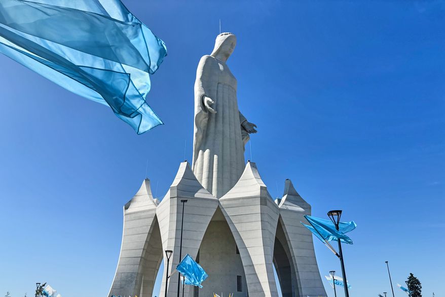 Flags wave in the wind in front of an enormous statue of the Virgin Mary that is believed to be Europe's tallest during the inauguration in the village Konotopie, Poland, Saturday, Aug. 15, 2026. (AP Photo/Claudia Ciobanu)