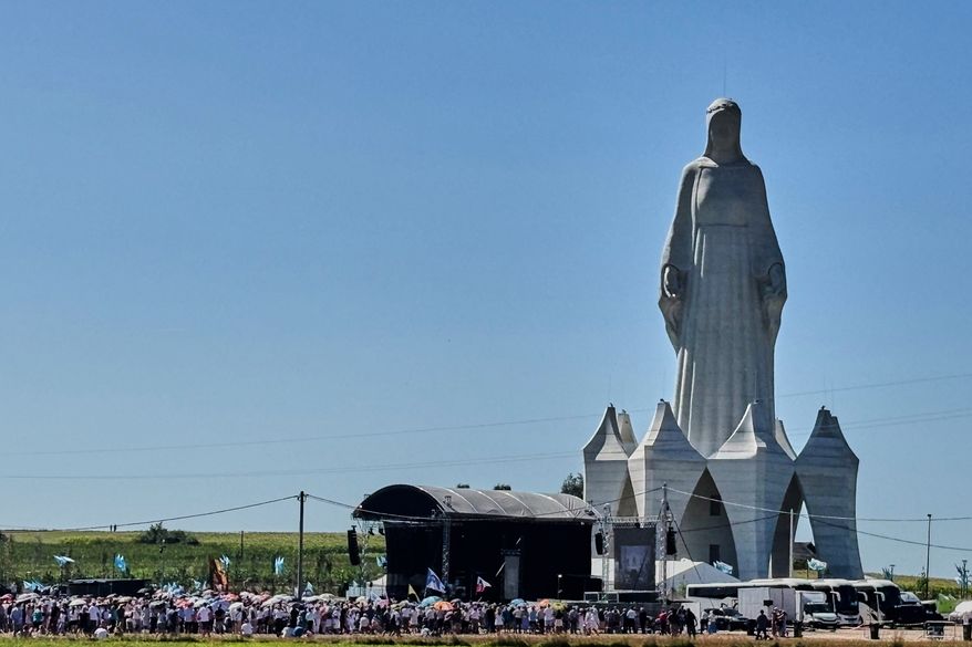 People gather near an enormous statue of the Virgin Mary that is believed to be Europe's tallest during the inauguration in the village Konotopie, Poland, Saturday, Aug. 15, 2026. (AP Photo/Claudia Ciobanu)