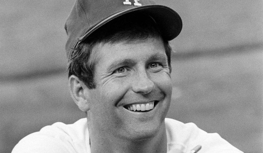 Lefthander Tommy John of the Los Angeles Dodgers signs an autograph before a game, Aug. 12, 1977. (AP Photo/Lennox McLendon, File)