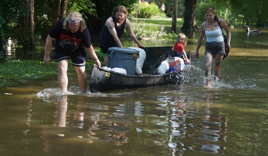 Scott Conrad, left, Joseph Workman, second from left, Ronan Carey, in the boat, and Kesley Patterson use a kayak to transport items from their flooded homes in Indianapolis, Sunday, Aug. 16, 2026. (AP Photo/Obed Lamy)