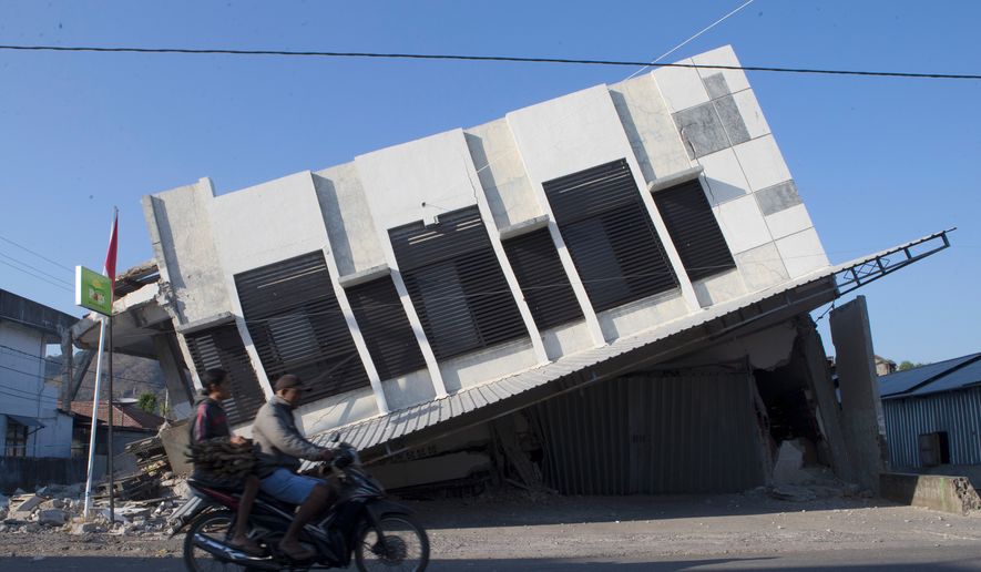 Motorists ride past a building that collapsed during an earthquake in Reo, East Nusa Tenggara province, Indonesia, Monday, Aug. 17, 2026. (AP Photo/Firdia Lisnawati)