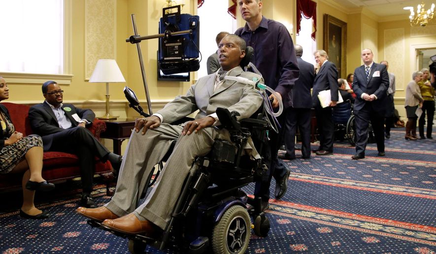 FILE - Former Baltimore Ravens NFL football player O.J. Brigance, center, current senior advisor to player development, is pushed by a nurse outside of a committee room in Annapolis, Md., March 10, 2015, after testifying to Maryland lawmakers against a right-to-die bill. (AP Photo/Patrick Semansky, File)