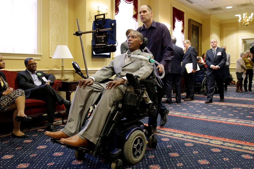 FILE - Former Baltimore Ravens NFL football player O.J. Brigance, center, current senior advisor to player development, is pushed by a nurse outside of a committee room in Annapolis, Md., March 10, 2015, after testifying to Maryland lawmakers against a right-to-die bill. (AP Photo/Patrick Semansky, File)