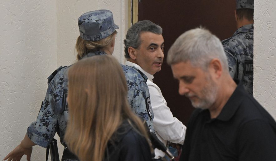 Lev Shlosberg, center, senior member of the Yabloko party, is being led out of the court room after a judge convicted him and sentenced him to more than 11 years in prison, in a court in Pskov, Russia, Monday, Aug. 17, 2026. (AP Photo)