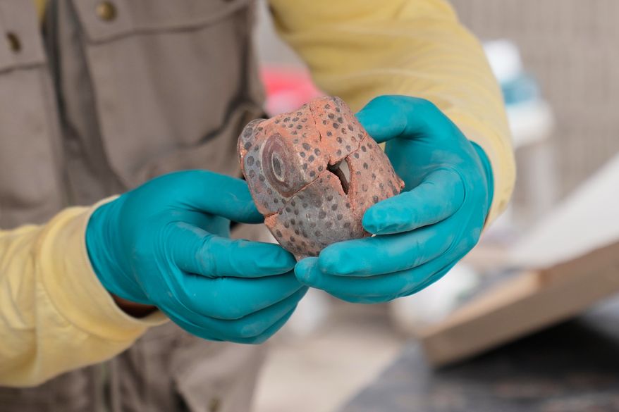 An archaeologist holds up a ceramic snake head that he unearthed while excavating skeletal remains at the Huaca Pucllana archaeological site in Lima, Peru, Tuesday, Aug. 18, 2026. The findings are from the Lima culture, according to the excavation's leader Gladys Paz. (AP Photo/Martin Mejia)