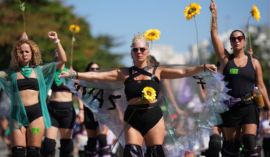 Women protest for stronger laws to combat misogyny and femicide on Copacabana beach in Rio de Janeiro, Sunday, Aug. 2, 2026. (AP Photo/Silvia Izquierdo)