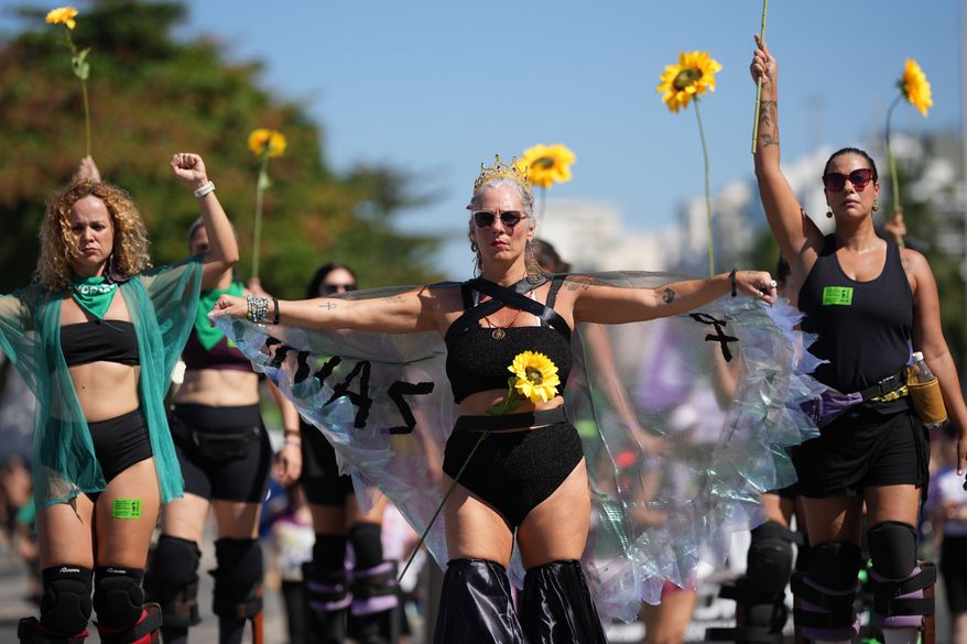 Women protest for stronger laws to combat misogyny and femicide on Copacabana beach in Rio de Janeiro, Sunday, Aug. 2, 2026. (AP Photo/Silvia Izquierdo)