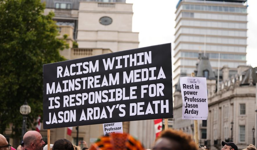 People hold signs during a vigil held by Stand Up to Racism in memory of late University of Cambridge professor Jason Arday at Trafalgar Square in London, Monday, Aug. 17, 2026. (AP Photo/Kirsty Wigglesworth)