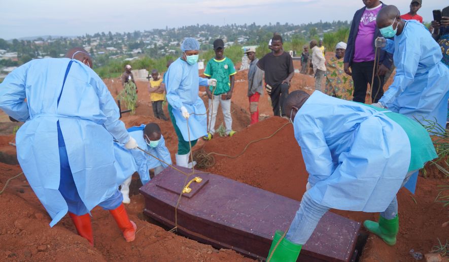 People dressed in protective gear lower into a grave the coffin containing the remains of 6-year-old Baudjo Baraka Jules, who died of Ebola, in Bunia, Ituri province, eastern Congo, Tuesday, Aug. 18, 2026. (AP Photo/Dieudonne Dirole)