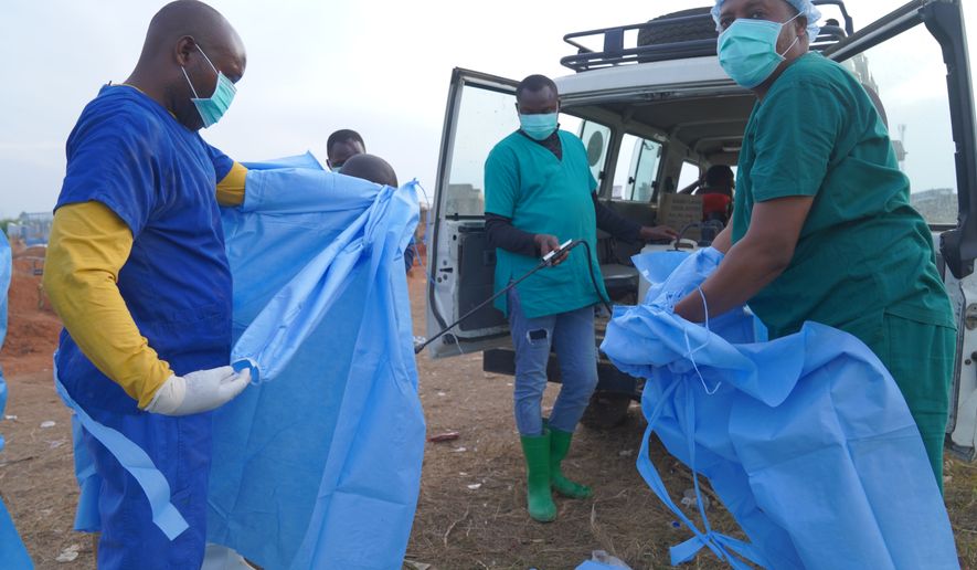 A health worker sprays a colleague with disinfectant after taking part in a burial service for 3-year-old Mave Mercienne, who died of Ebola, in Bunia, Ituri province, eastern Congo, Tuesday, Aug. 18, 2026. (AP Photo/Dieudonne Dirole)