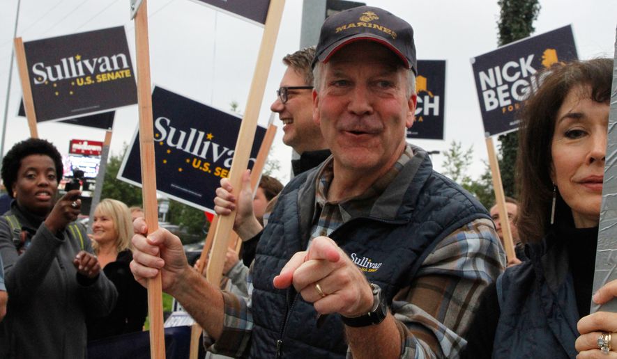 Sen. Dan Sullivan, R-Alaska, points to a passing motorist during morning rush hour traffic in Anchorage, Alaska, Tuesday, Aug. 18, 2026. (AP Photo/Mark Thiessen)
