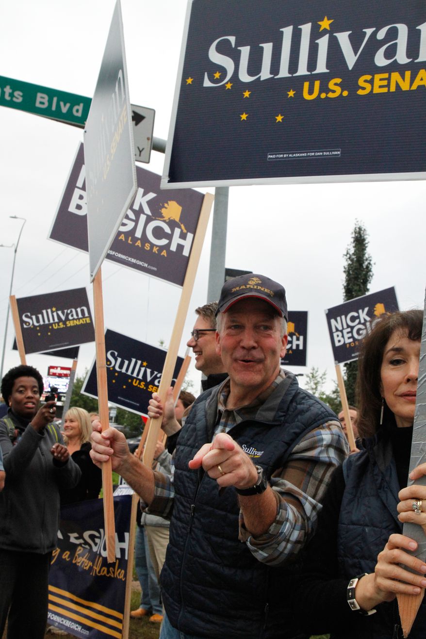 Sen. Dan Sullivan, R-Alaska, points to a passing motorist during morning rush hour traffic in Anchorage, Alaska, Tuesday, Aug. 18, 2026. (AP Photo/Mark Thiessen)