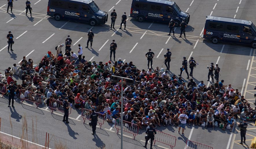 Migrants who crossed from Morocco into Spain are escorted by Spanish police to temporary shelters after being cleared from a beach in the Spanish exlave of Ceuta on Thursday, Aug. 20, 2026. (AP Photo/Antonio Sempere)